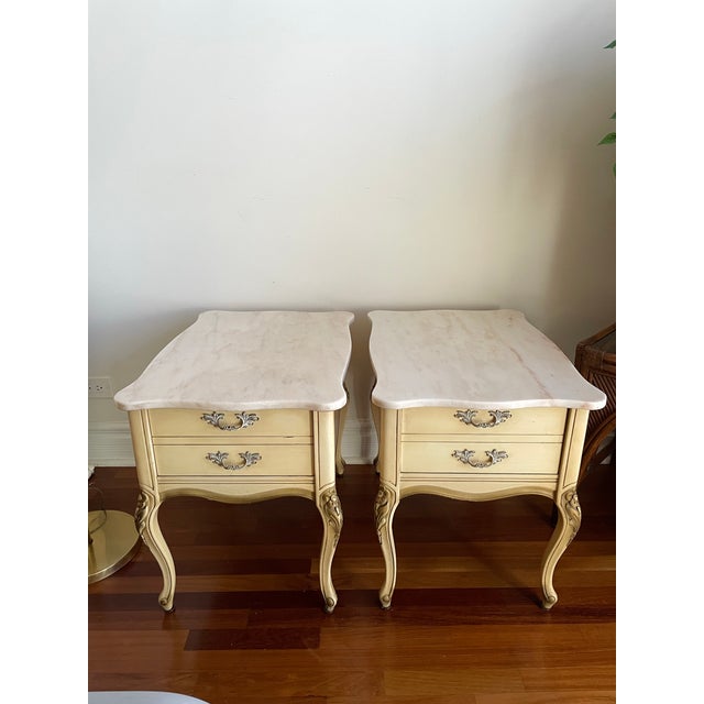 Elegant pair of vintage Country French –style nightstands featuring softly shaped marble tops and hand-finished cream-...