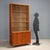 Larch veneered storage unit with brass accents, featuring a display case and hinged doors. In good overall condition, with...