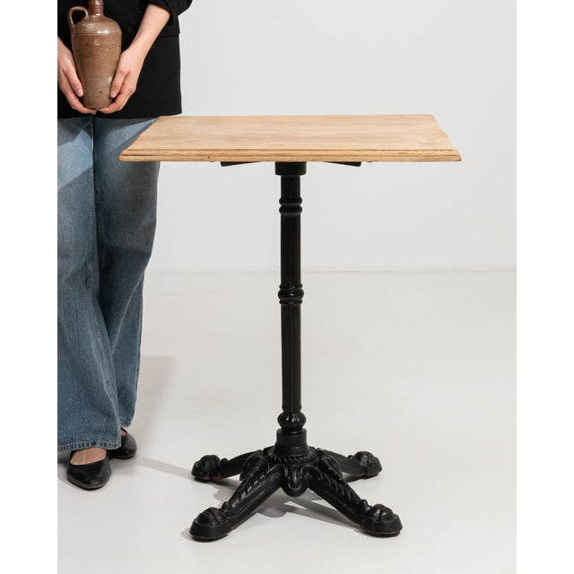 An authentic French bistro table combining a sturdy cast iron base with a warm oak top. The contrast of materials creates...