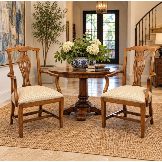 A handsome pair of mahogany armchairs in the Georgian style, featuring shaped crest rails, decorative pierced backs,...