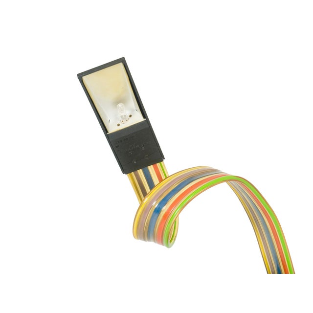 Table lamp with flexible multicolored extruded pvc stem with electrical cabling rising from a polycarbonate weighted base....
