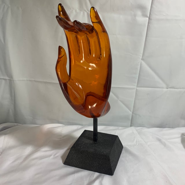 Offered here is a lovely Buddha hand lucite sculpture mounted on a black stand.