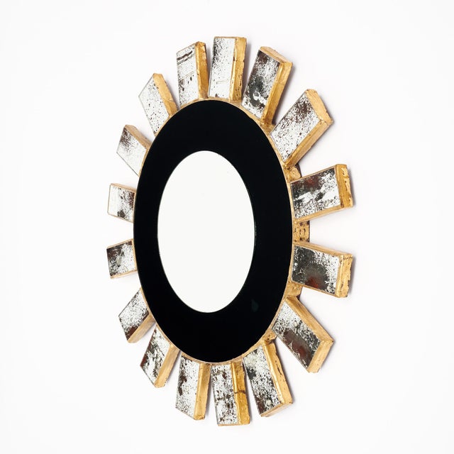 Sunburst mirror from Spain featuring a central circular mirror surrounded by a black glass frame. The mirror is made with...