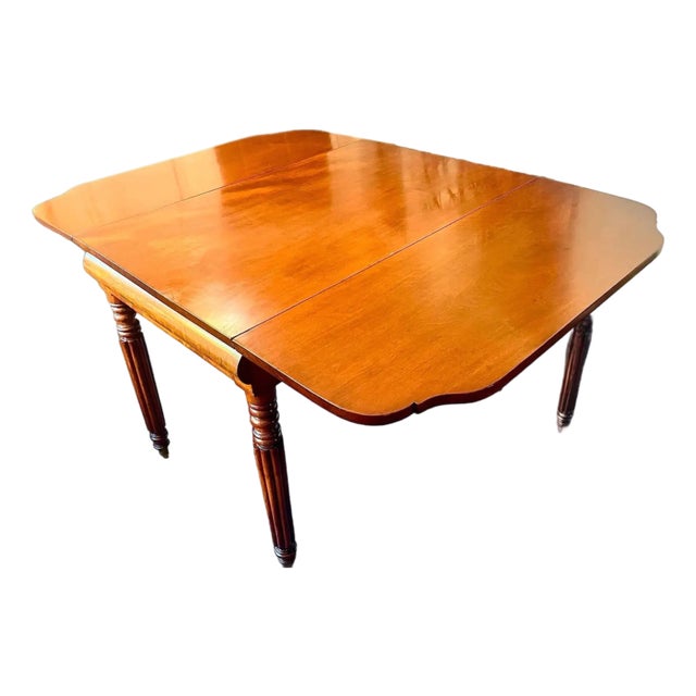 Handsome drop leaf table, thick reeded legs with turned detail, terminating in brass casters. Single drawer in mahogany...