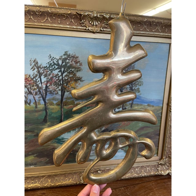 Vintage cast metal wall plaque in the form of the Chinese "Shou" character, symbolizing longevity. This sculptural piece...