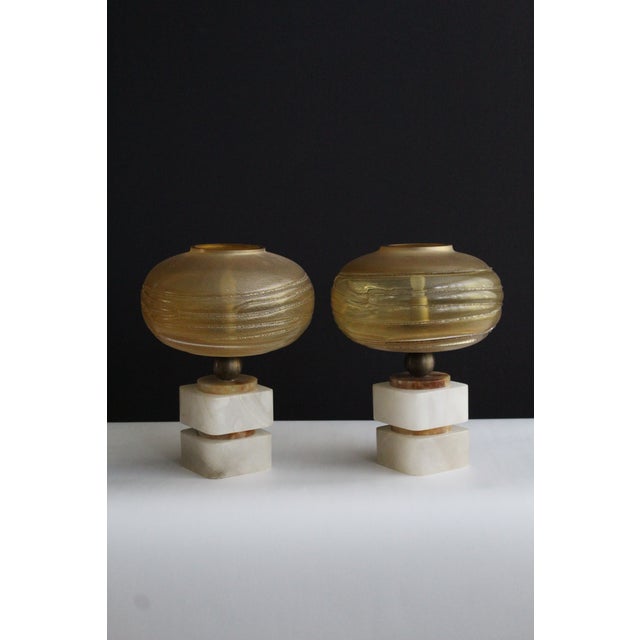 Petite pair of Italian Art Deco lamps Piero Chiesa influence. Hand blown Murano glass globes mounted on carved and...