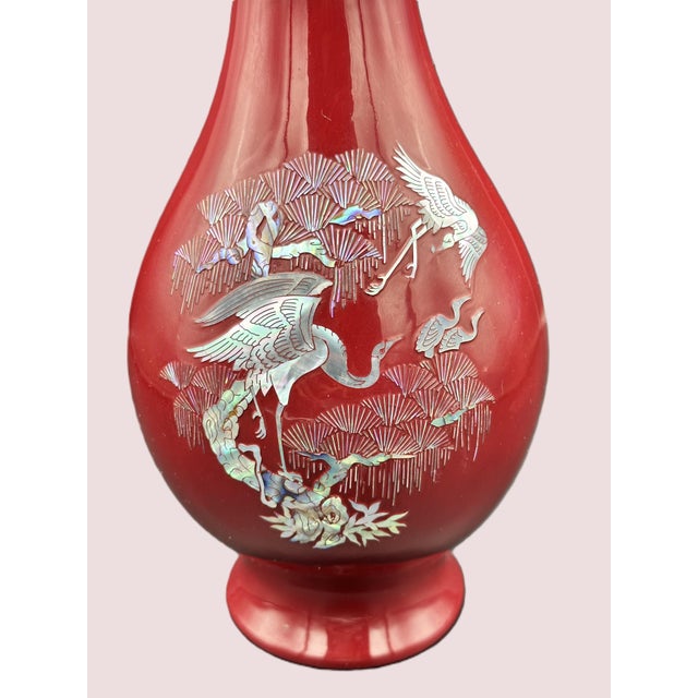 A striking Korean lacquer vase featuring intricate mother of pearl (Najeon) inlay depicting cranes in flight among...