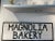 Original Magnolia Bakery hand-painted sign from an upper state New York bakery. White background with black lettering,...