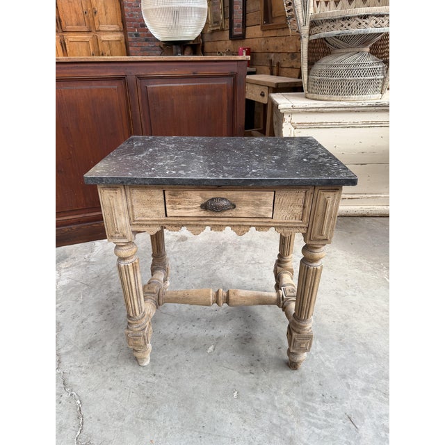 This antique butcher's table has been completely restored. It features a gray marble top and a carved beechwood base. It...
