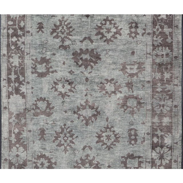 Measures: 9'3 x 13'9. This modern Indian Oushak rug has been hand-knotted in wool and features a sub-geometric design...