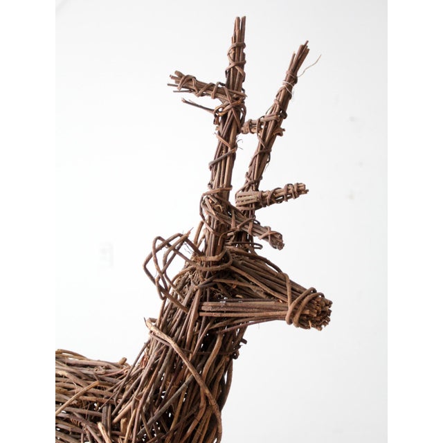 A vintage wicker reindeer with a warm, natural tone and a tall, expressive silhouette. The woven branches form an organic...