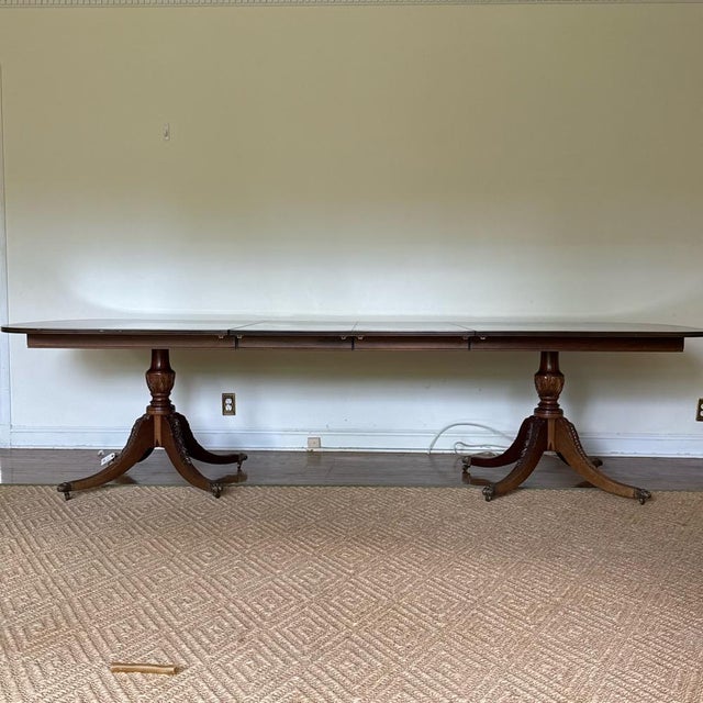 A vintage Georgian style flame-figured mahogany double-pedestal dining table with three 20” extension leaves, a long...