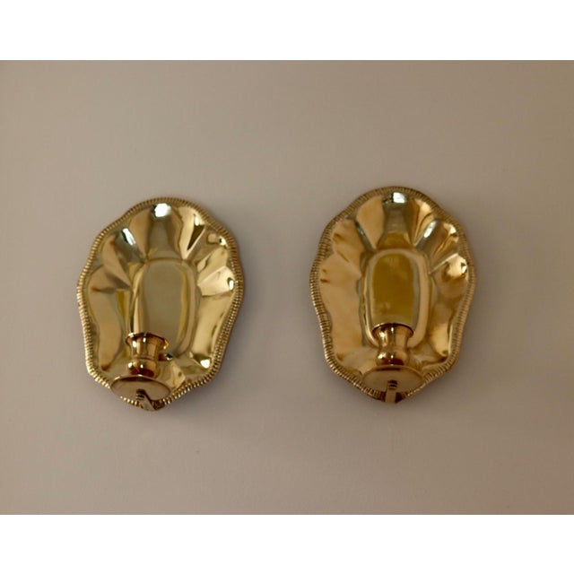 Made in Sweden. A captivating set of Swedish mid-century wall sconces with elegantly curved brass edges. These exquisite...
