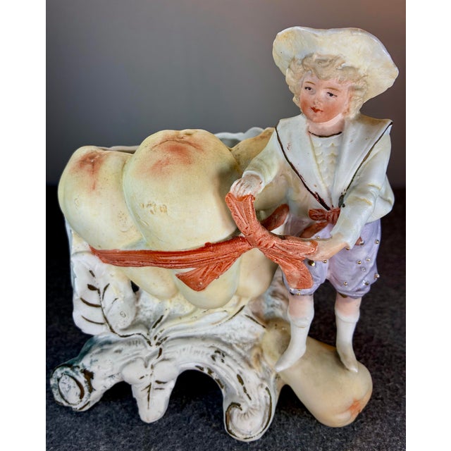 Featuring a young boy in a sailor-style outfit beside a large fruit or vessel design.
