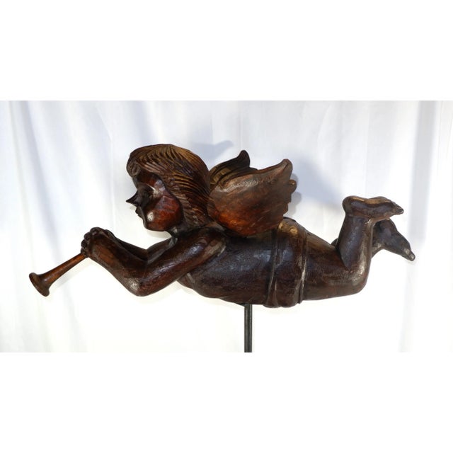 An antique large wood carved angel blowing a trumpet. Angel was a paper mache mold. Angel sits on a wood and metal base....