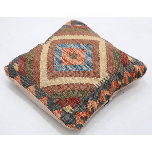 A one-of-a-kind handwoven Afghan wool kilim accent pillow featuring central diamond medallion in blue and red on cream....
