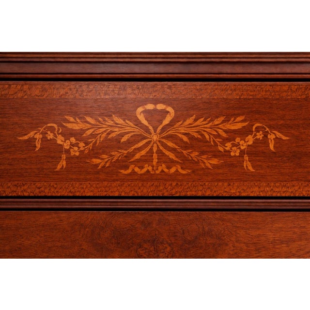 Circa 1900 mahogany five-drawer chest with ribbon inlay, bookmatched flame veneer, fluted legs, and original brass rosette...