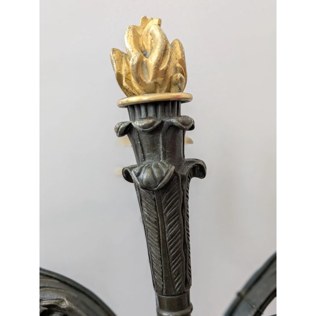 French Empire Bronze Dore Candelabrum featuring a cast gilded flame encircled by five arms ending in gilded sconces below...