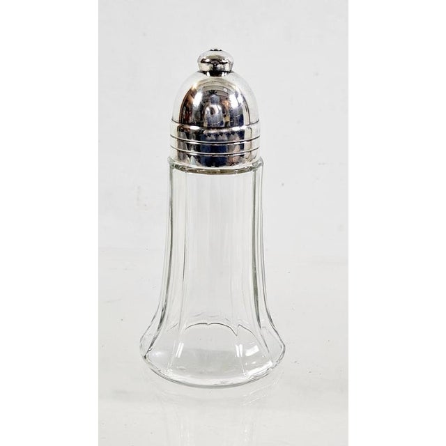 Elegant Art Deco sugar shaker by Christofle, France. This refined muffineer features a clear fluted glass body with a...