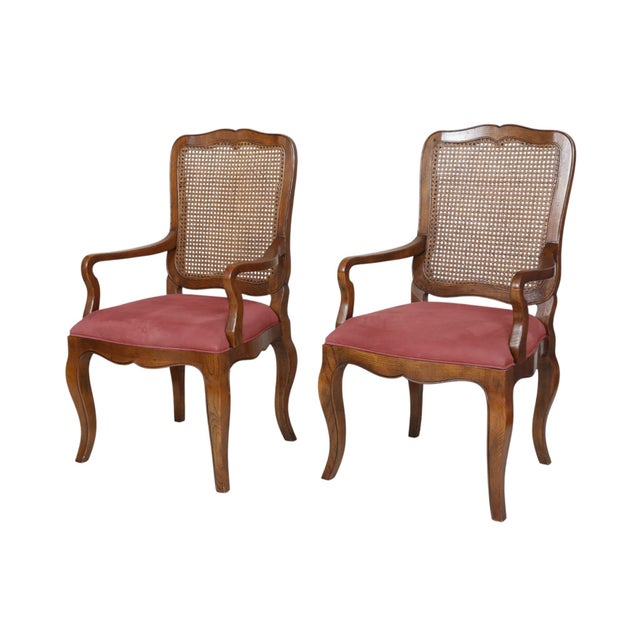 A pair of French Country style armchairs made by Baker Furniture. Oak frames are carved with simple serpentine curves and...