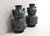 This pair of cloisonné enamel vases consists of a body in two parts. The lowest, cylindrical in shape, depicts scenes of...