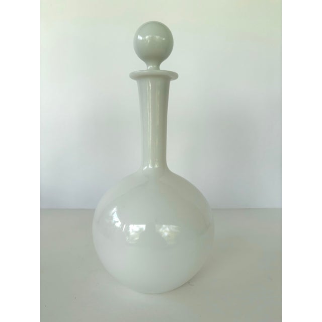 This elegant mid-century milk glass bath oil bottle features a classic bulbous body with a tall, slender neck and a...