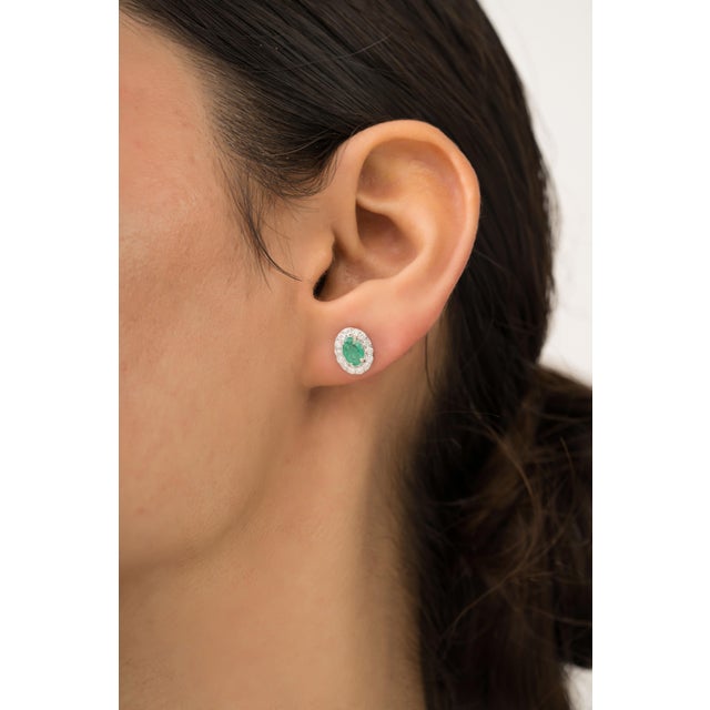 These elegant stud earrings featuring 0.83 carat of oval-cut emeralds set in 14K white gold at the center. The emerald...