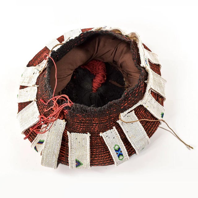 Married Zulu women always keep their heads covered in public. For ceremonial occasions, they wear elaborately woven red...
