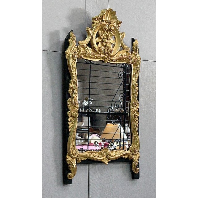 Chic small wall mirror in golden wood, Louis XV style, with black painted wood support. This decorative object is composed...