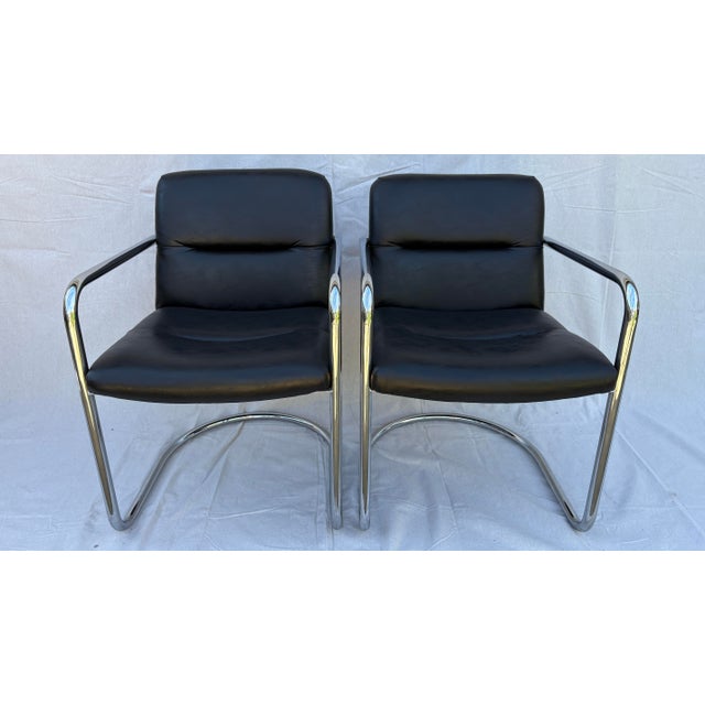 Striking set of four vintage cantilever armchairs featuring polished tubular chrome frames and supple black vegan leather...