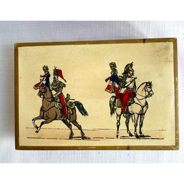 This mid century decorative hinged lid stamp or trinket box features a French Epinal style print. The box is lacquered red...