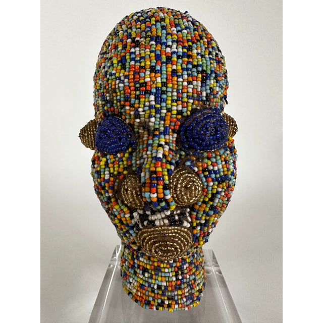 Beaded head from Cameroon on lucite plinth. Having a clay foundation, and meticulously adorned with multi-color beading...
