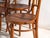 A set of four antique chairs in bentwood, with a curved crest rail over vertical splats and a moulded board seat....
