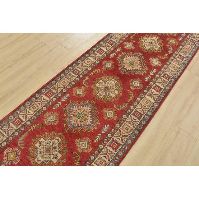 A tribal Caucasian Kazak runner hand-knotted with fine wool on a cotton foundation. This rug features a row of geometric...