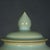 A round, softly curved porcelain jar with its lid, finished in a celadon-green glaze with a fine crackle (ice-crackle)...