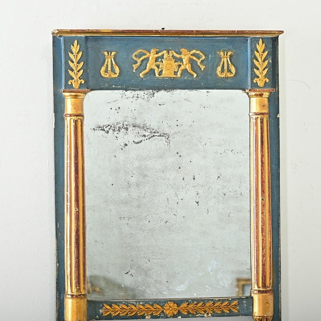 A Neoclassical inspired trumeau mirror from 19th century France, with stylized motifs in parcel gilt. In the center of the...