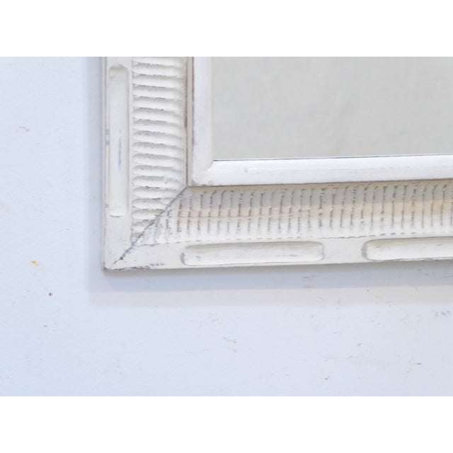 This carved wood, whitewashed mirror measures 30.5"H x 21.25"W.