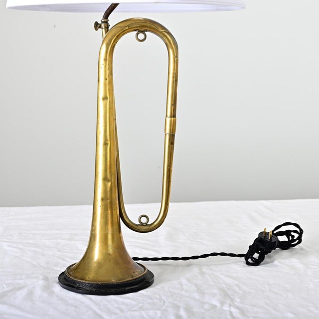 A vintage Couesnon brass trumpet made in France that has been upcycled into a one-of-a-kind table lamp. The horn shows...