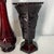 The items shown are vintage ruby red glass pieces from the Avon 1876 Cape Cod Collection, featuring a tall bud vase and an...