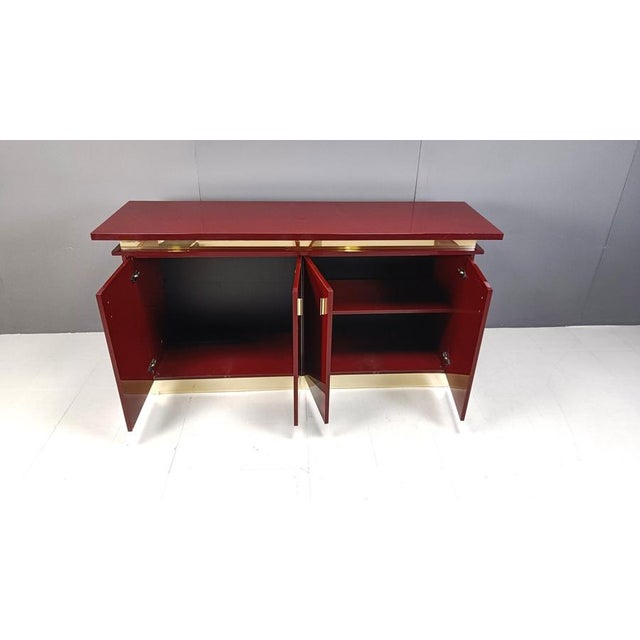 High gloss red lacquered sideboard with brass hardware. Beautiful and luxurious piece. Good overall condition with normal...
