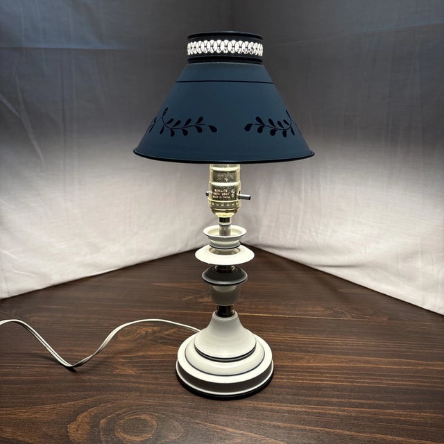 Beautiful vintage toleware table lamp featuring a classic white metal base paired with a coordinating blue leaf patterned...