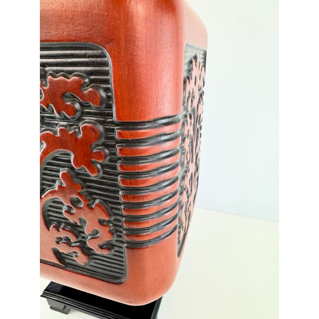 A striking vintage Chinoiserie-style table lamp featuring a rich red-orange ceramic body accented with raised black floral...