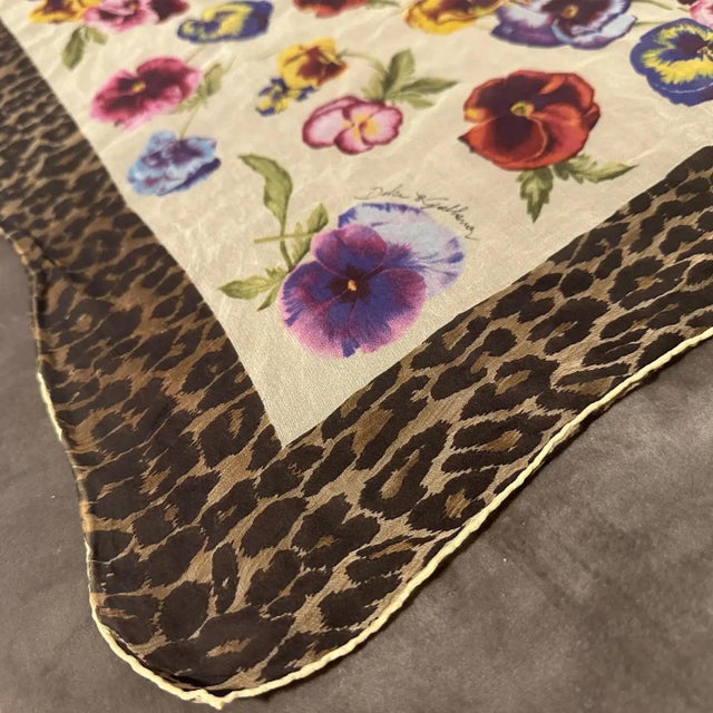 This is a Dolce & Gabbana scarf featuring a vibrant and eclectic design that blends natural and bold motifs. At the...