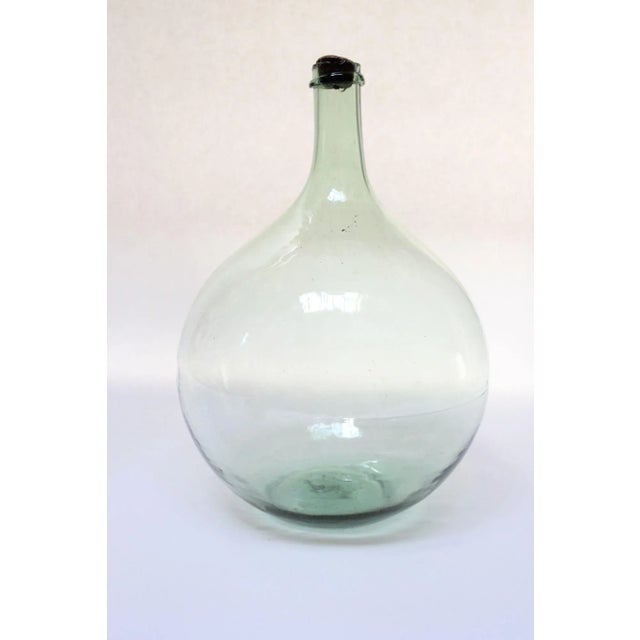 Pale green demijohn/carboy originally used for transporting wine (ca. Early 20th Century, France). Composed of 'blown-to-...
