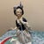 This elegant vintage porcelain figurine depicts a woman in refined Rococo-style attire, characterized by its ornate and...