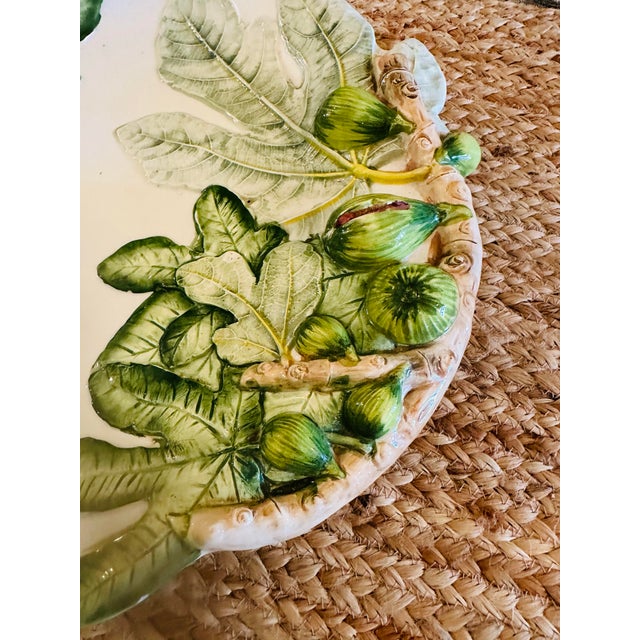 This is a charming Italian ceramic platter featuring a raised, hand-painted fig motif. The design wraps asymmetrically...