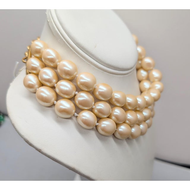1980s or 1990s goldtone 3-strand off-white faux-baroque pearls collar necklace with hook clasp. Marked "©Monet" on the...