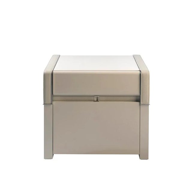 This bedside table is made of beige wood with gloss lacquered and engraved leather. The handmade methods used, result in...