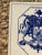 A classic Dutch Delft-style hand painted blue and white porcelain tile featuring an intricately rendered heraldic coat of...
