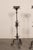 A French pair of black iron single candlestick floor lamps from the mid 20th century. This vintage pair of candle lights...